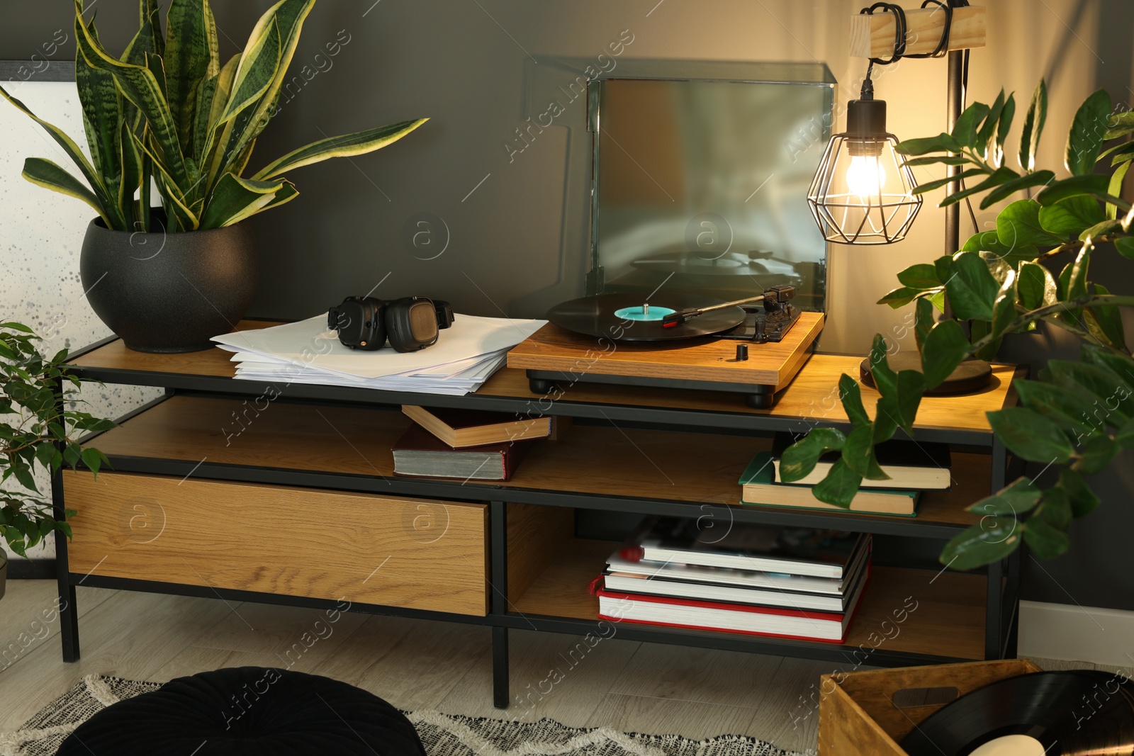 Photo of Stylish turntable with vinyl record on tv table in cozy room