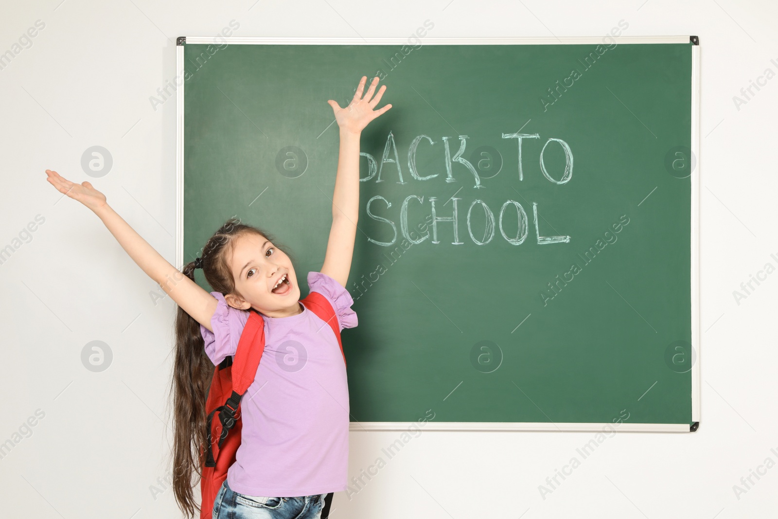 Photo of Little child near chalkboard with text BACK TO SCHOOL