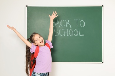 Little child near chalkboard with text BACK TO SCHOOL