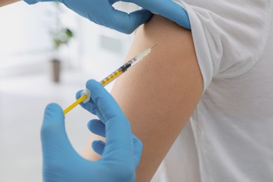 Doctor giving injection to woman in hospital, closeup. Immunization concept