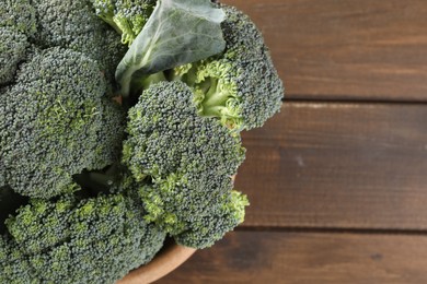 Bowl with fresh raw broccoli on wooden table, above view and space for text