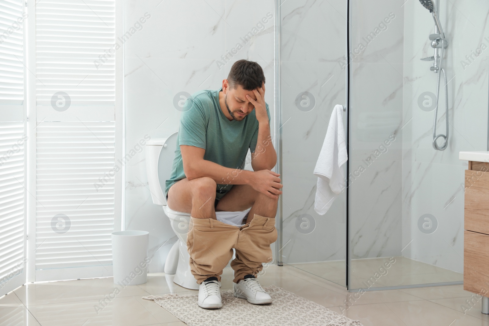 Photo of Man suffering from hemorrhoid on toilet bowl in rest room