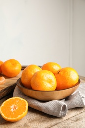 Photo of Bowl with ripe tangerines on wooden table