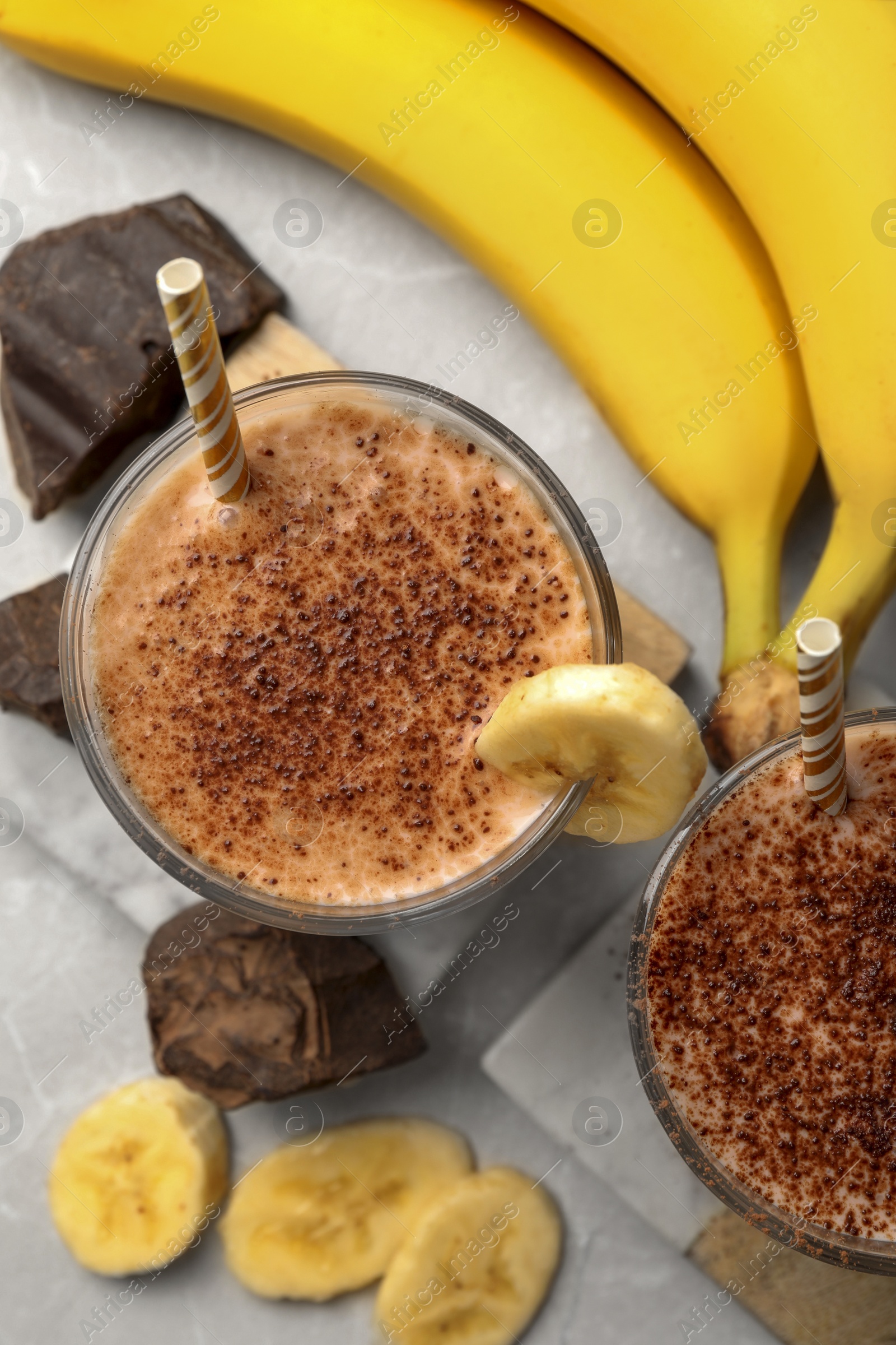 Photo of Tasty banana smoothie, fresh fruits and chocolate on white marble table, flat lay