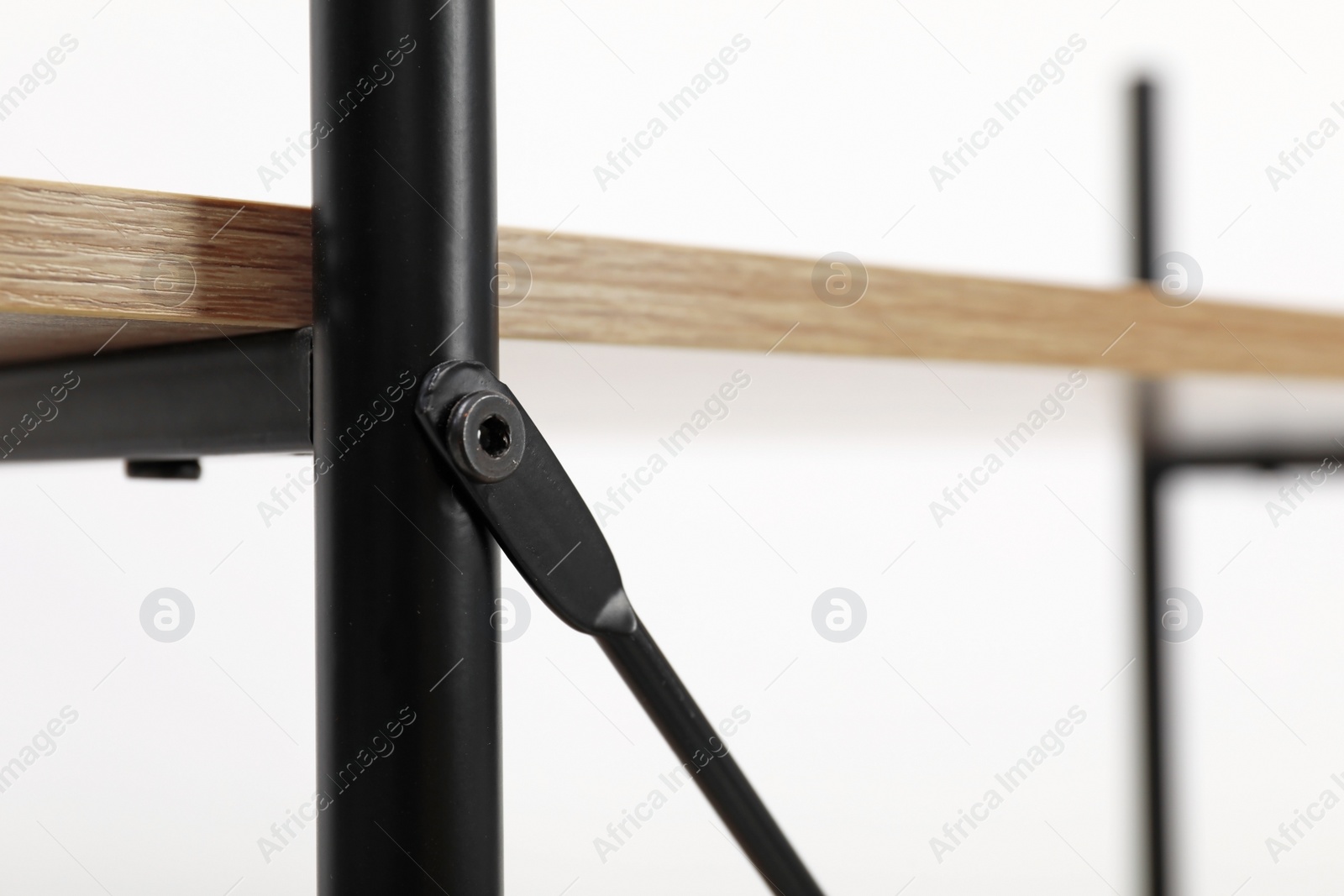 Photo of Rack with wooden shelf and metal joint on light background, closeup