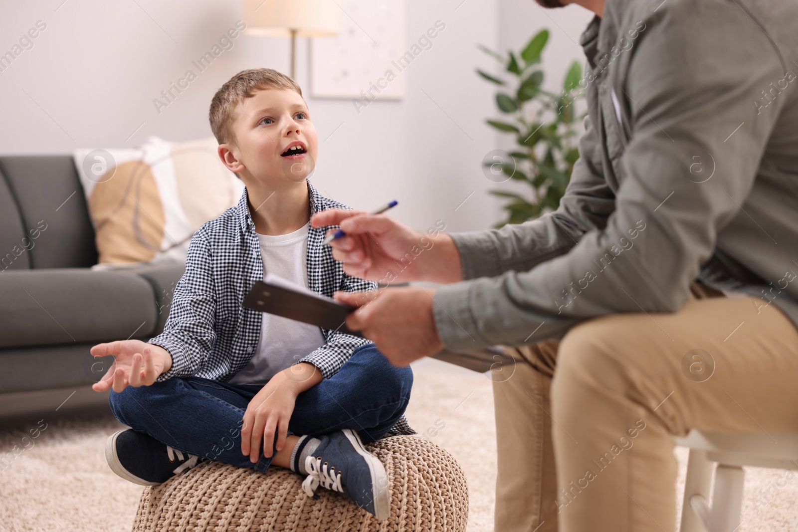 Photo of Dyslexia treatment. Speech therapist working with boy in room