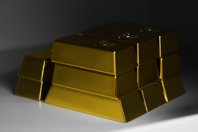 Many gold bars on white textured table, closeup