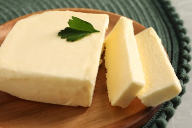 Photo of Cut tasty butter with parsley on grey table, closeup