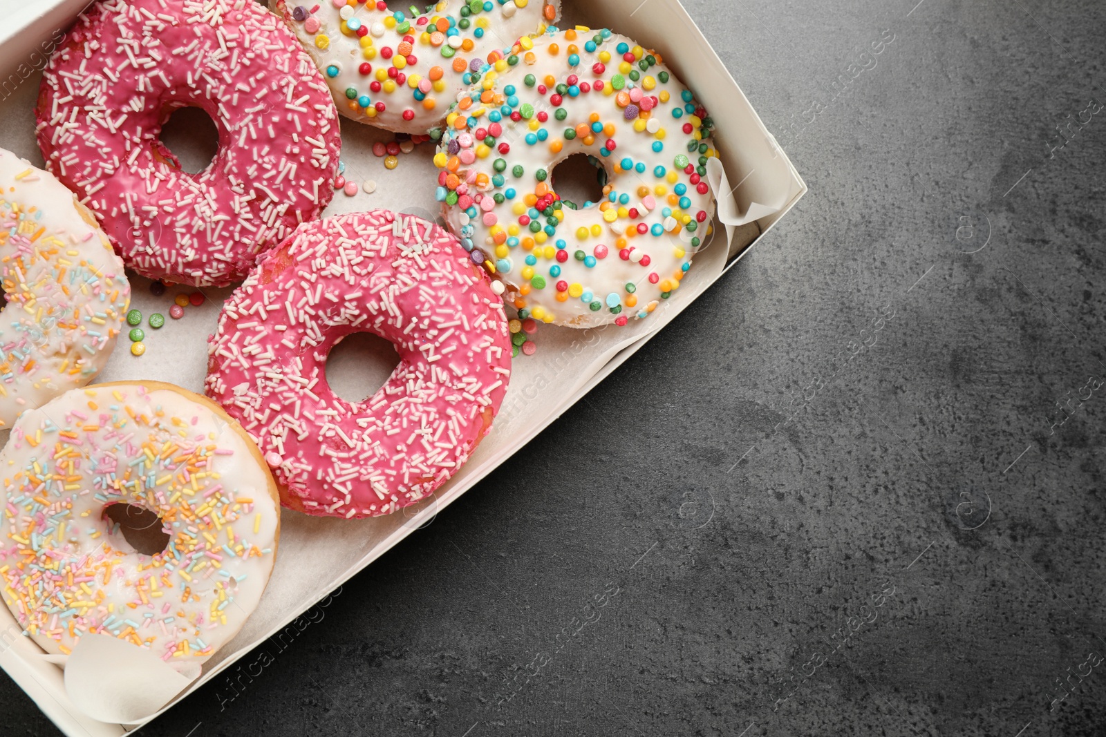 Photo of Delicious glazed donuts on grey table, top view. Space for text