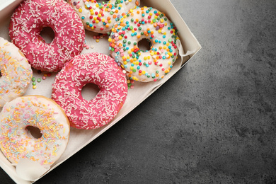 Photo of Delicious glazed donuts on grey table, top view. Space for text