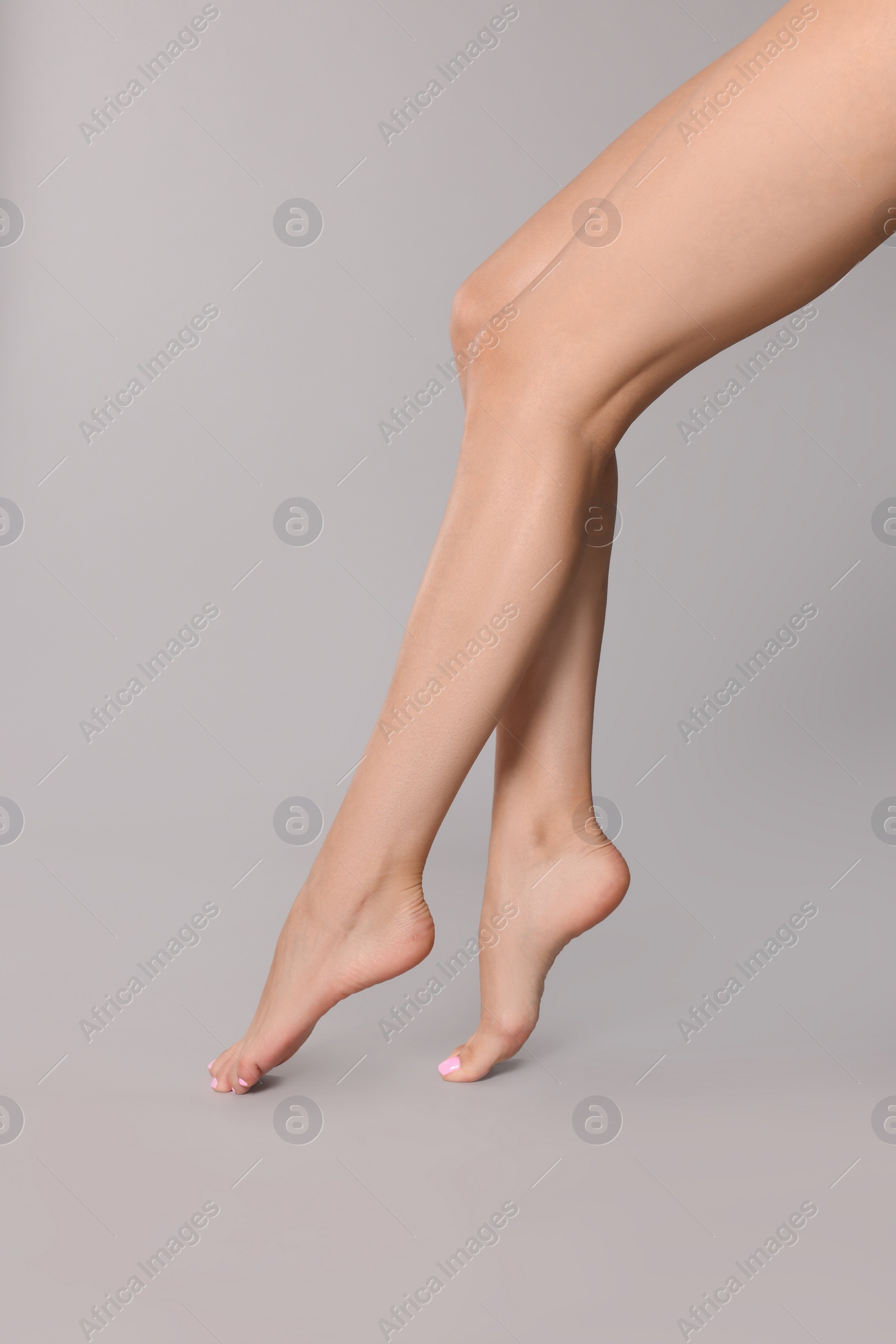 Photo of Woman with beautiful long legs on grey background, closeup