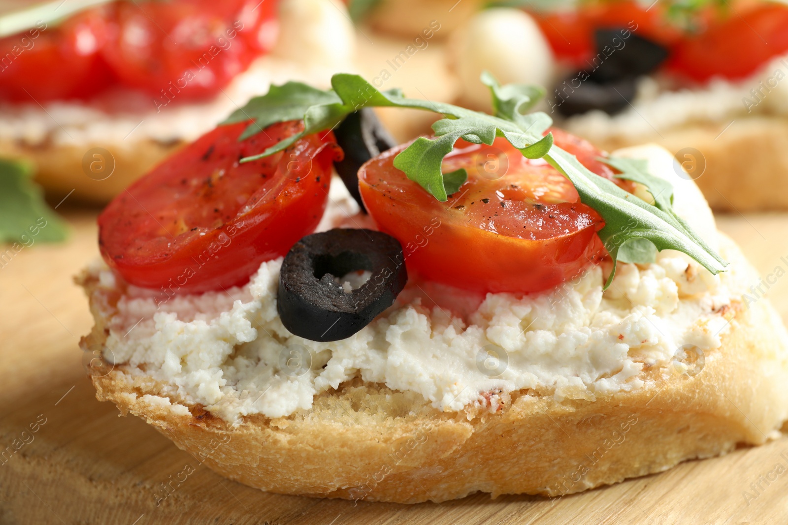 Photo of Delicious tomato bruschetta on wooden board, closeup