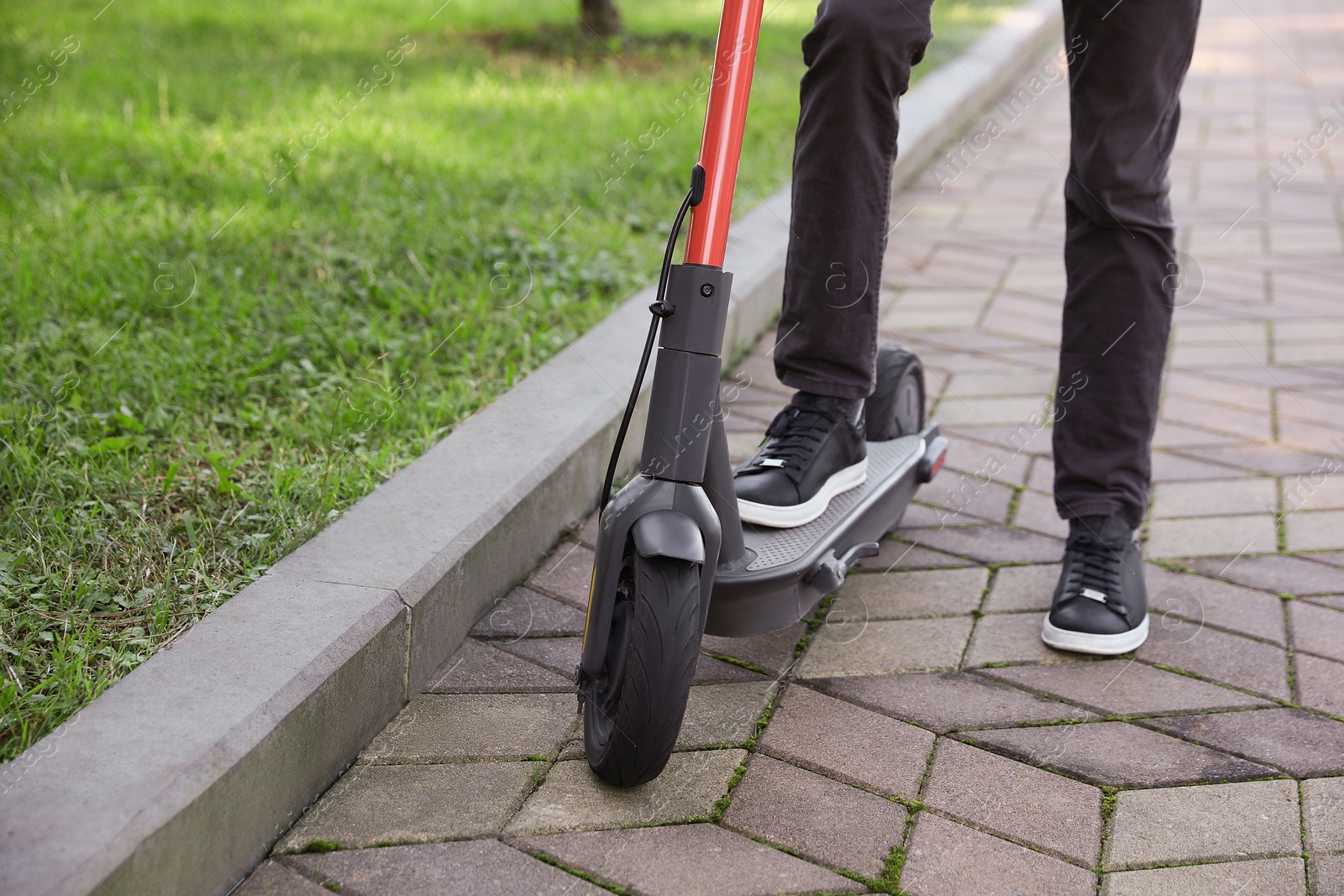 Photo of Man riding modern electric scooter in park, closeup