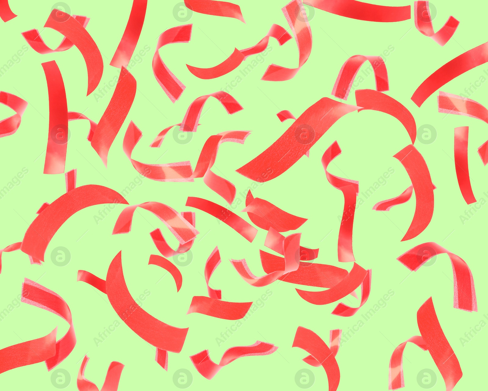 Image of Bright red confetti falling on light green background