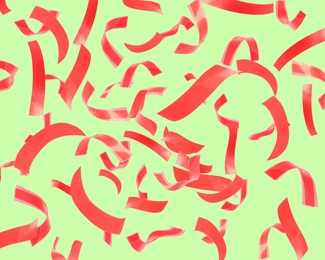 Image of Bright red confetti falling on light green background