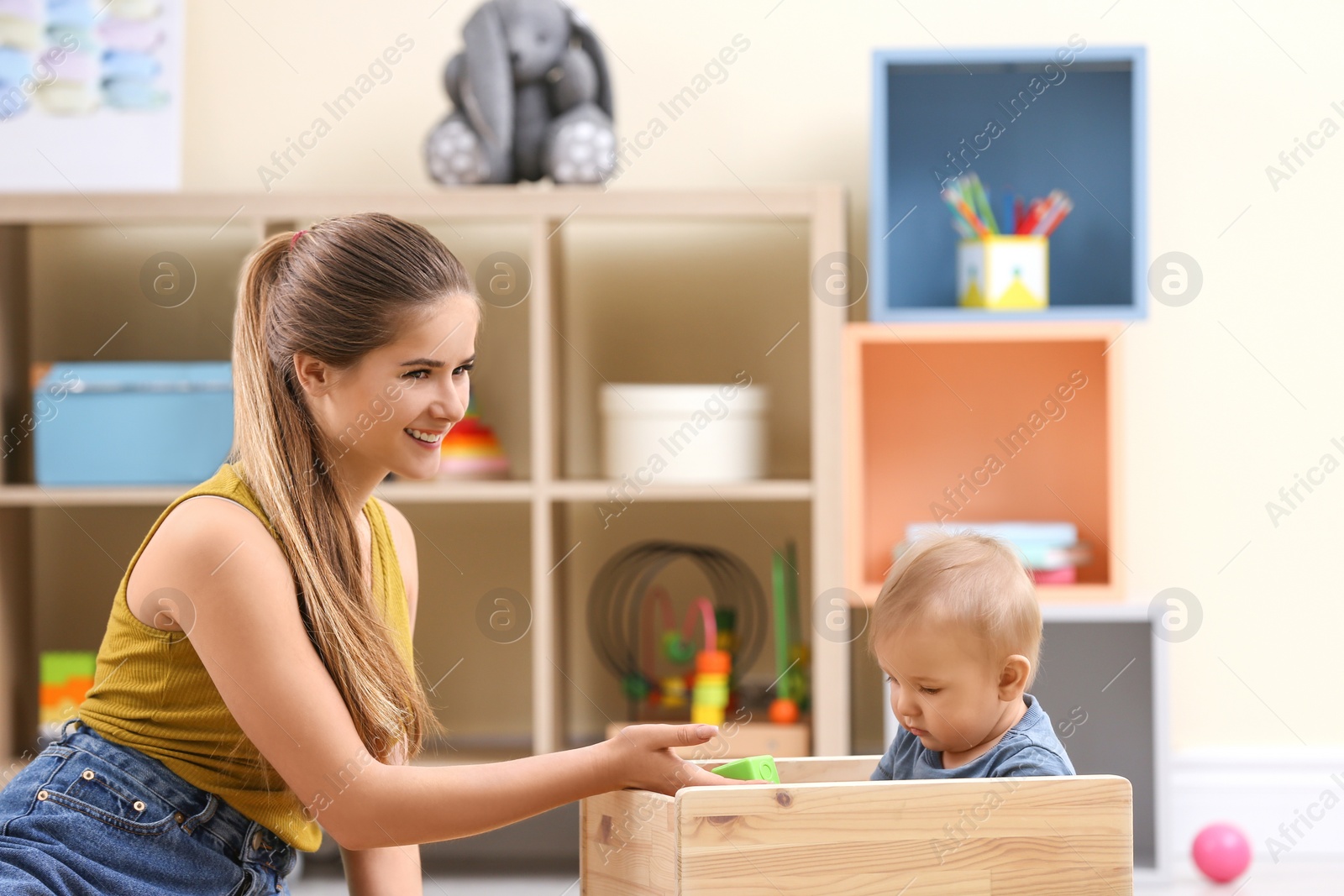 Photo of Teen nanny playing with cute little baby at home