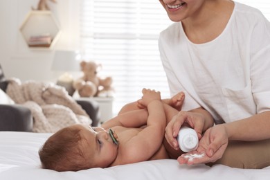 Mother with dusting powder near her cute baby at home, closeup. Space for text