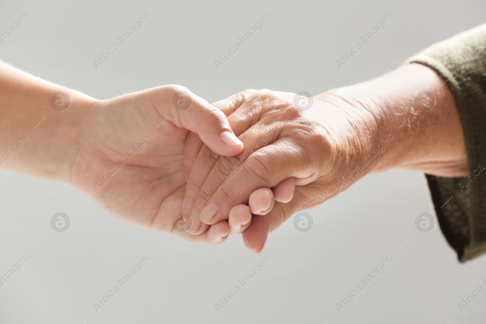 Photo of Helping hands on gray background, closeup. Elderly care concept