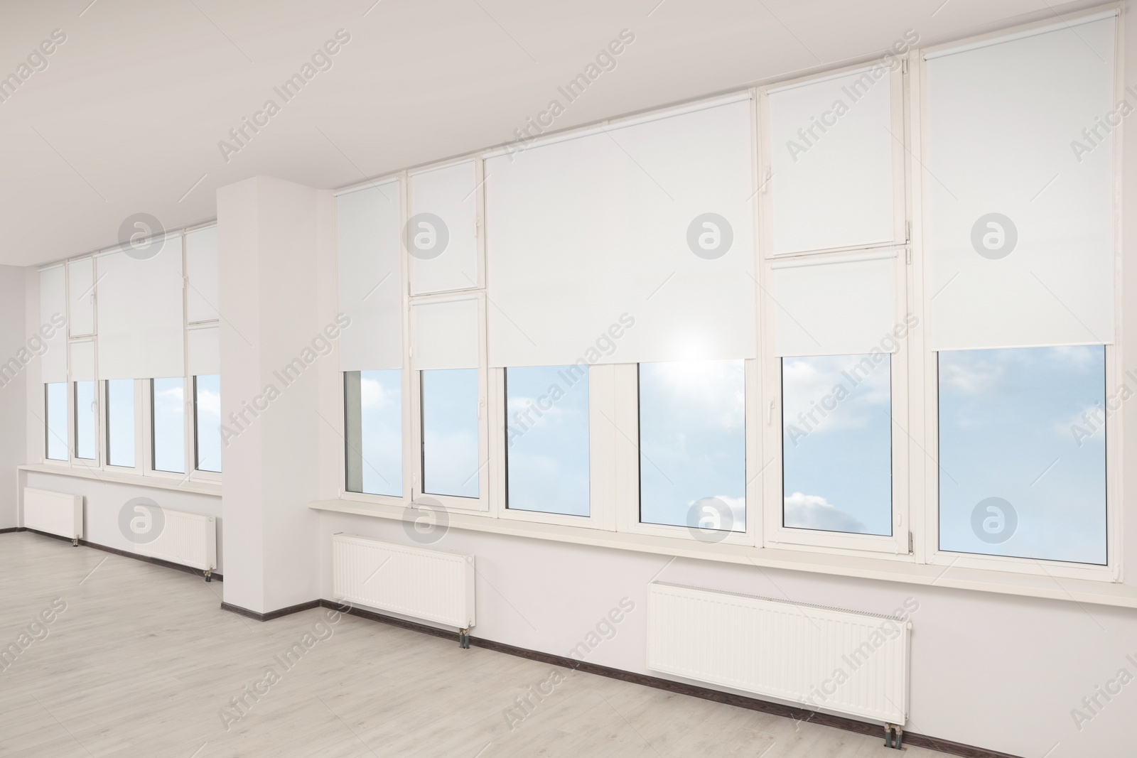 Photo of Plastic windows with white roller blinds indoors