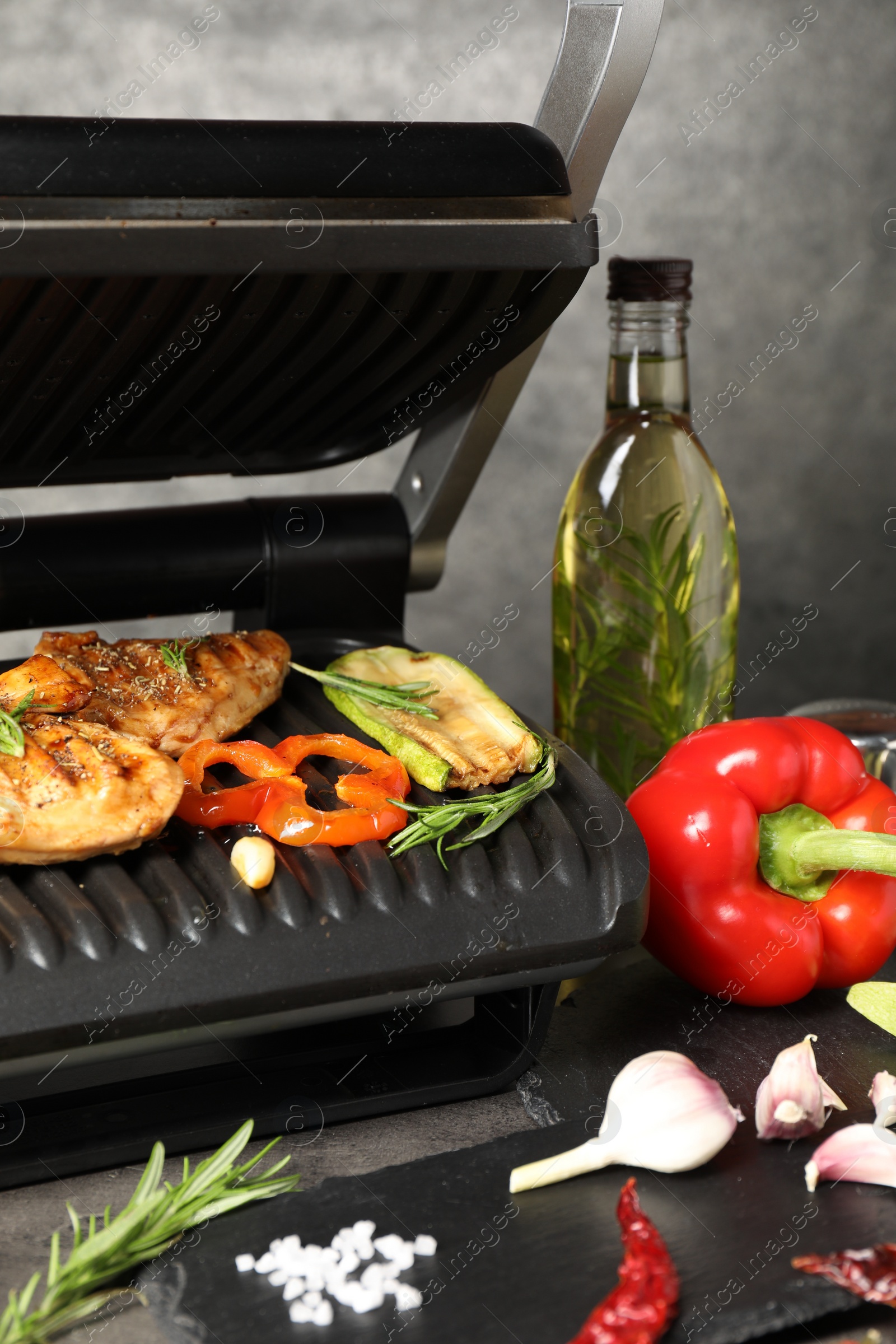 Photo of Electric grill with different products on grey table