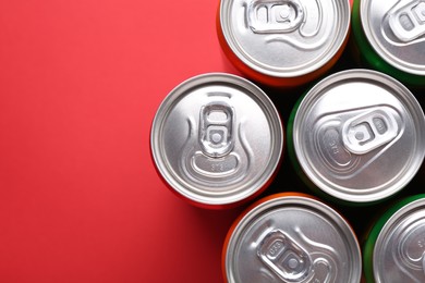 Energy drink in cans on red background, top view. Space for text