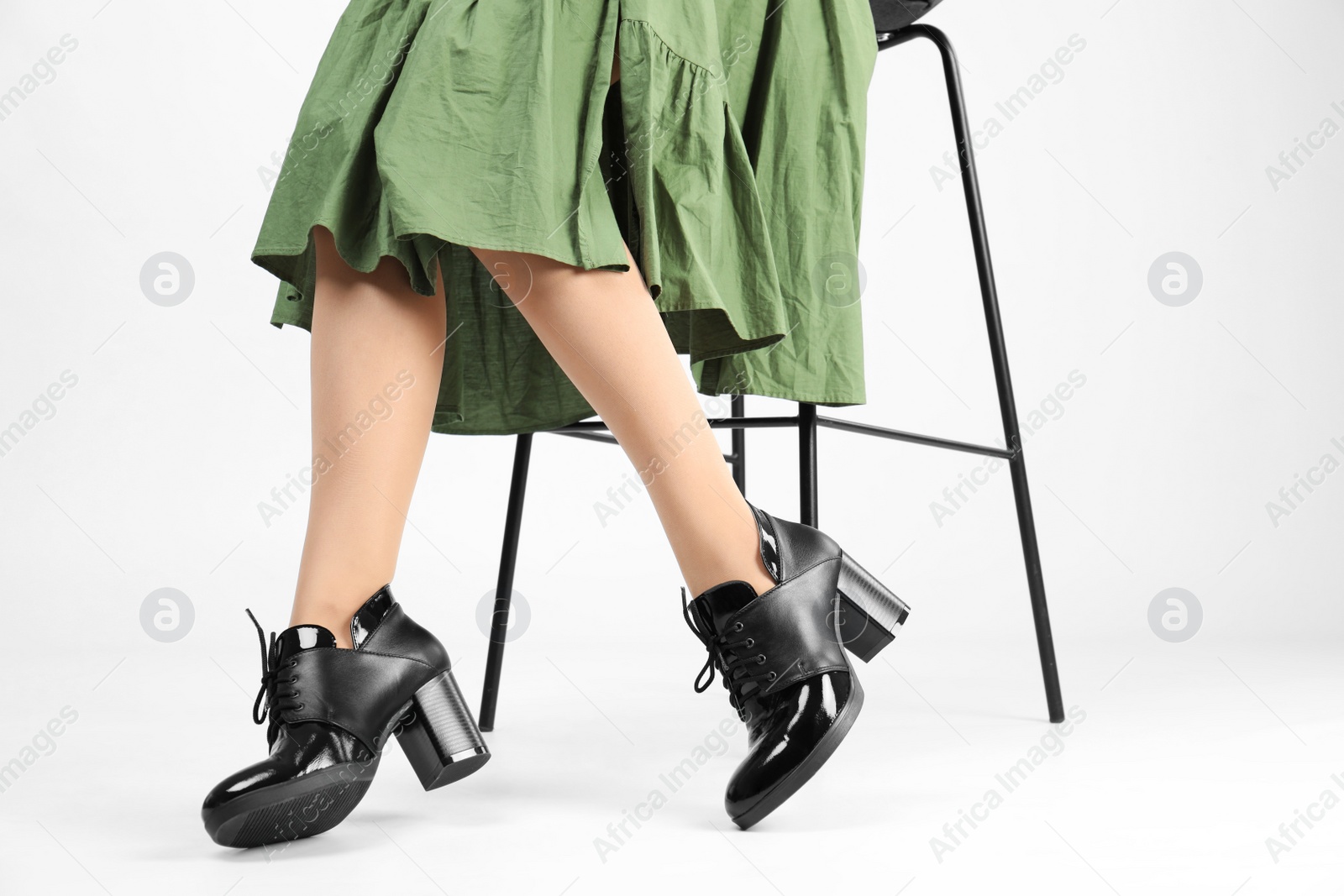 Photo of Woman in elegant shoes and bar stool on white background, closeup