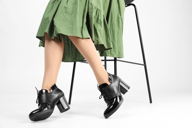 Woman in elegant shoes and bar stool on white background, closeup