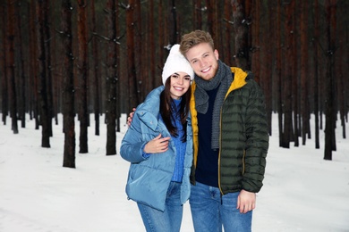 Beautiful young couple in snowy winter forest