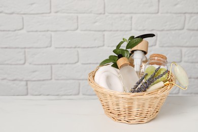 Photo of Spa gift set in wicker basket on white marble table. Space for text