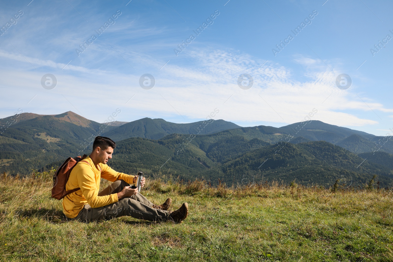 Photo of Tourist with thermos and backpack enjoying beautiful mountain landscape