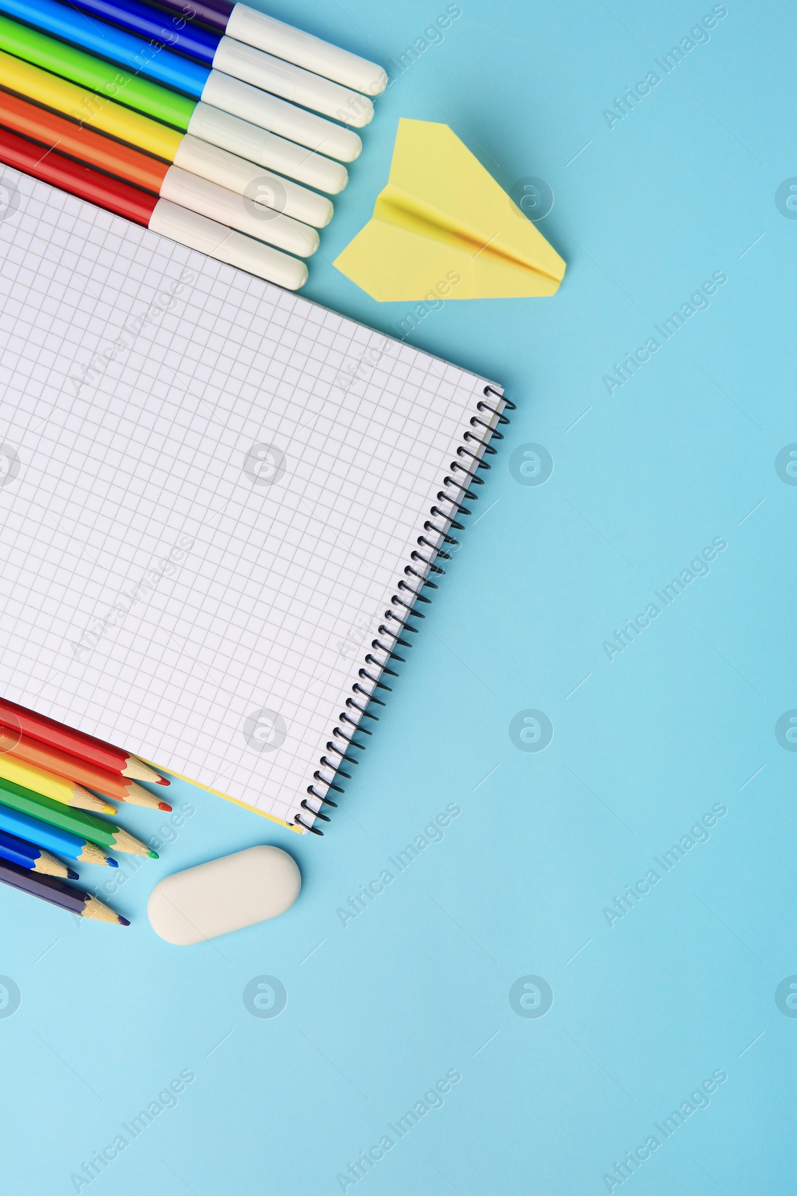 Photo of Flat lay composition with open notebook and other school stationery on light blue background, space for text. Back to school