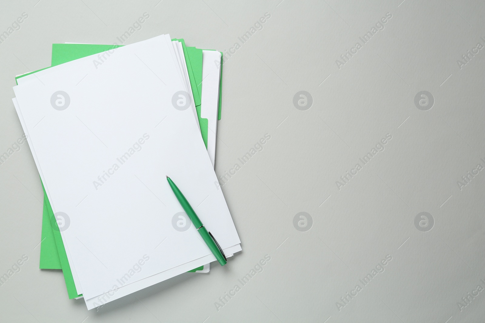 Photo of Green files with blank sheets of paper and pen on light grey background, top view. Space for text