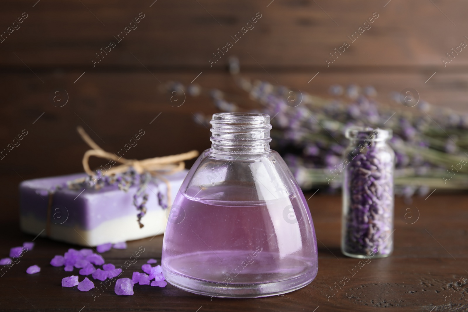 Photo of Bottle with aromatic lavender oil on wooden table