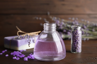 Photo of Bottle with aromatic lavender oil on wooden table