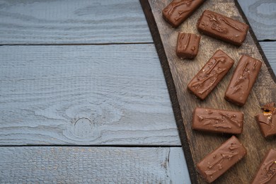 Photo of Delicious chocolate candy bars on grey wooden table, top view. Space for text