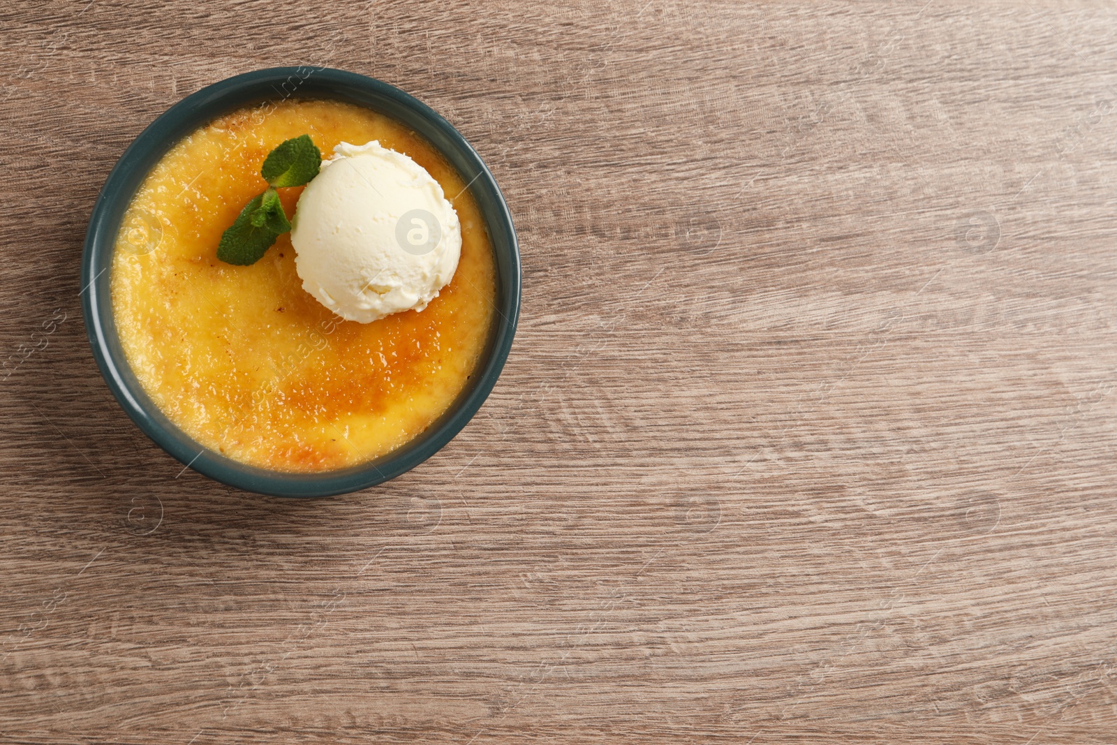 Photo of Delicious creme brulee with scoop of ice cream and mint on wooden table, top view. Space for text