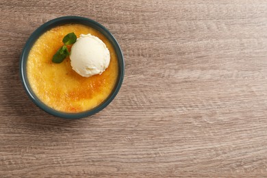 Delicious creme brulee with scoop of ice cream and mint on wooden table, top view. Space for text