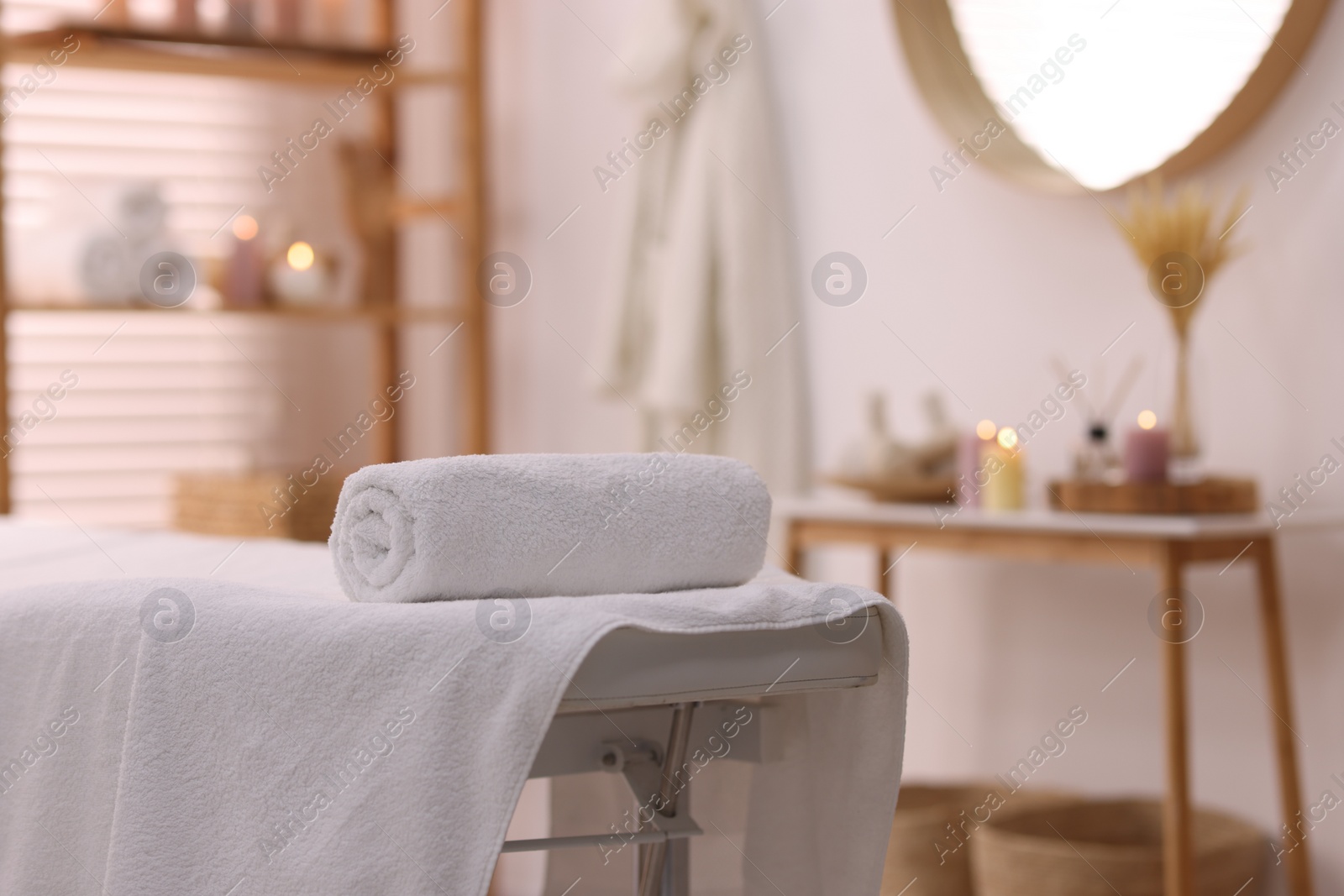 Photo of Rolled towel on massage table in spa center. Space for text