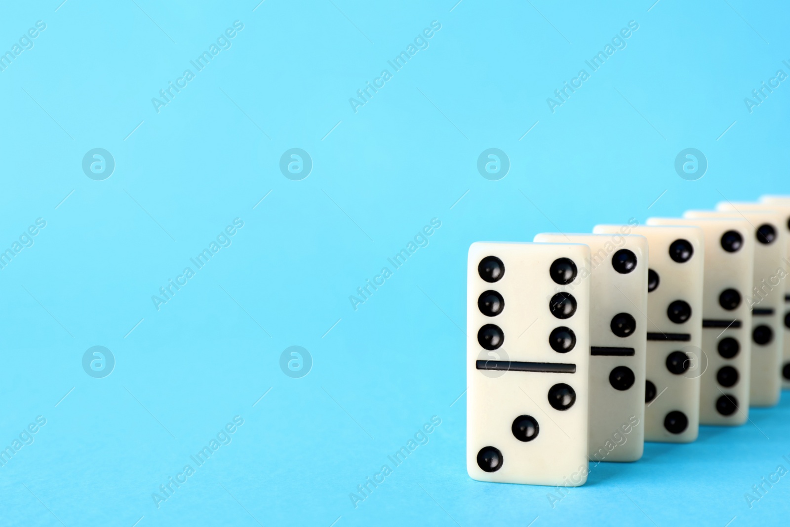 Photo of White domino tiles on turquoise background. Space for text
