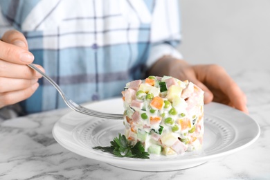 Photo of Young woman with delicious salad Olivier at marble table, closeup