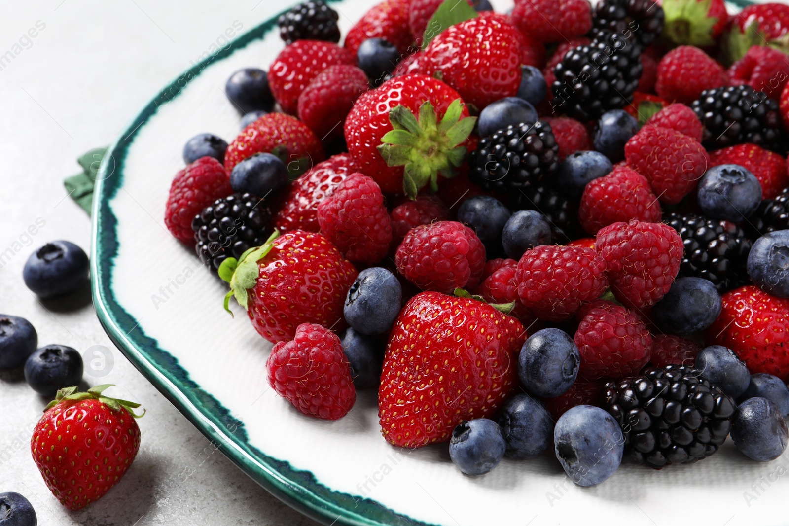 Photo of Different fresh ripe berries on light grey table, closeup