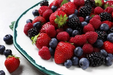 Different fresh ripe berries on light grey table, closeup