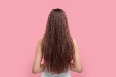 Photo of Woman with damaged messy hair on pink background, back view