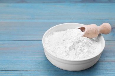 Photo of Bowl and scoop of natural starch on light blue wooden table. Space for text