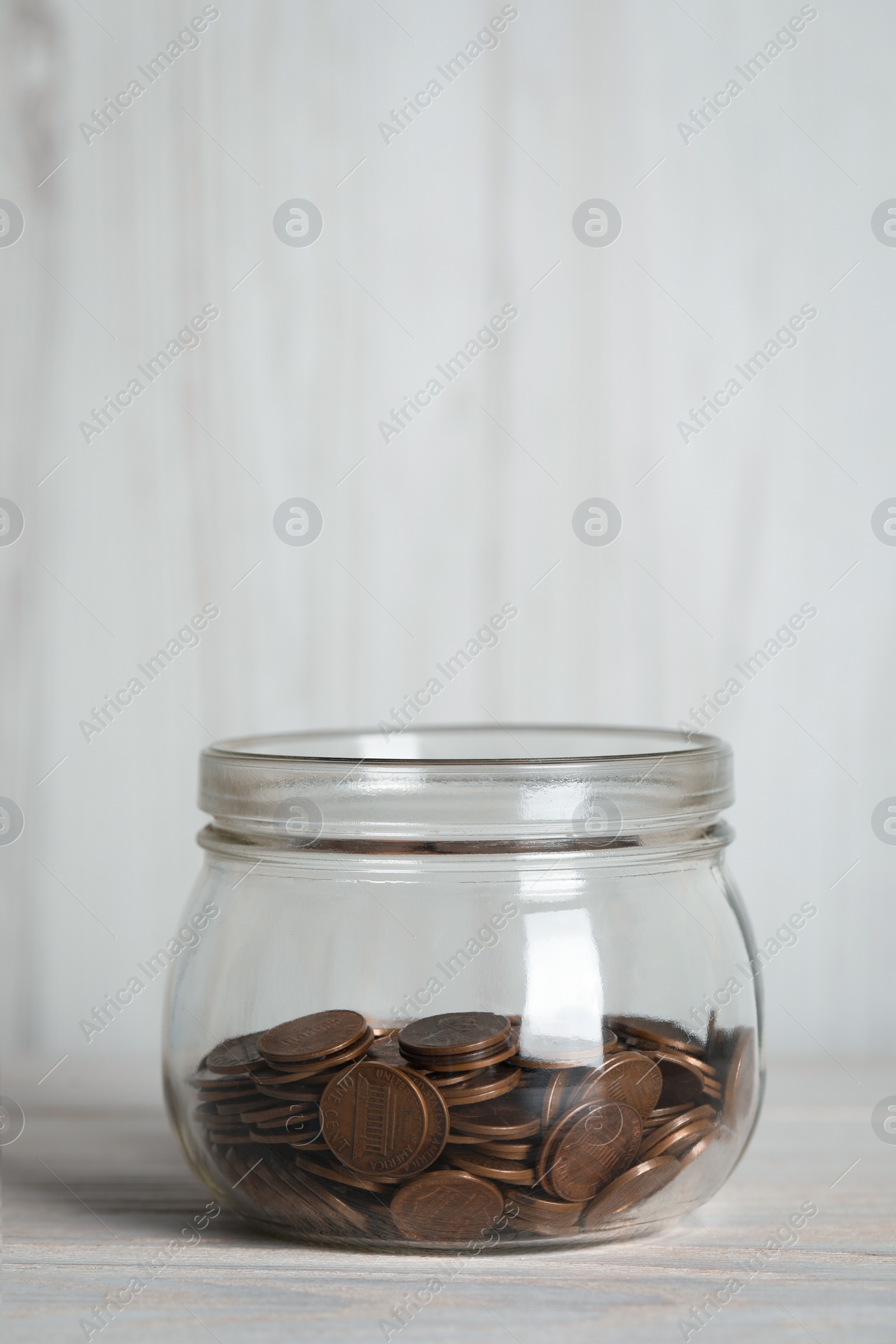 Photo of Glass jar with coins on white wooden table