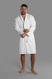 Photo of Happy young man in bathrobe on grey background