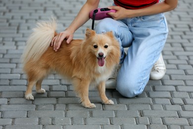 Photo of Young woman with her cute dog on city street, closeup