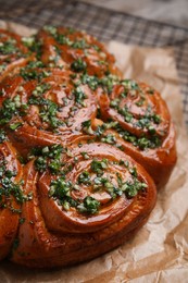 Photo of Traditional Ukrainian garlic bread with herbs (Pampushky) on parchment, closeup