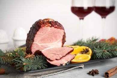 Photo of Delicious ham served with orange and fir branches on grey table, closeup. Christmas dinner