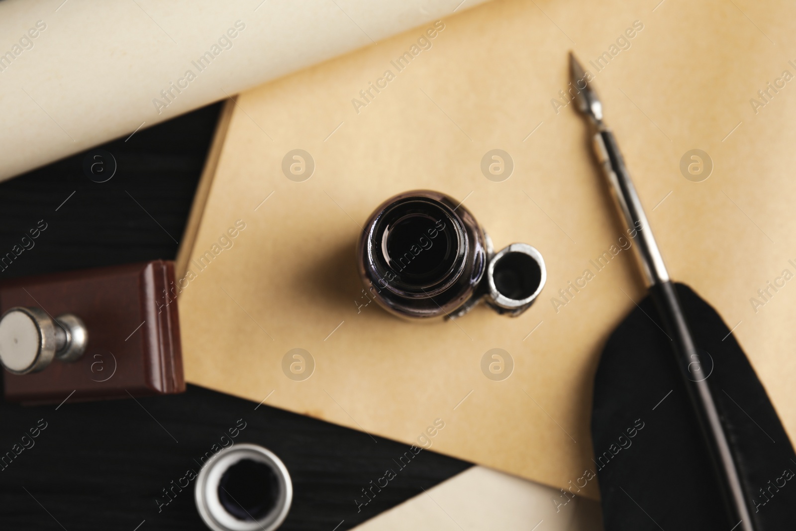 Photo of Feather pen, bottle of ink and paper on table, flat lay